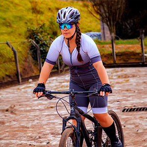 Mulher em cima da bicicleta com macacão,usando capacete
